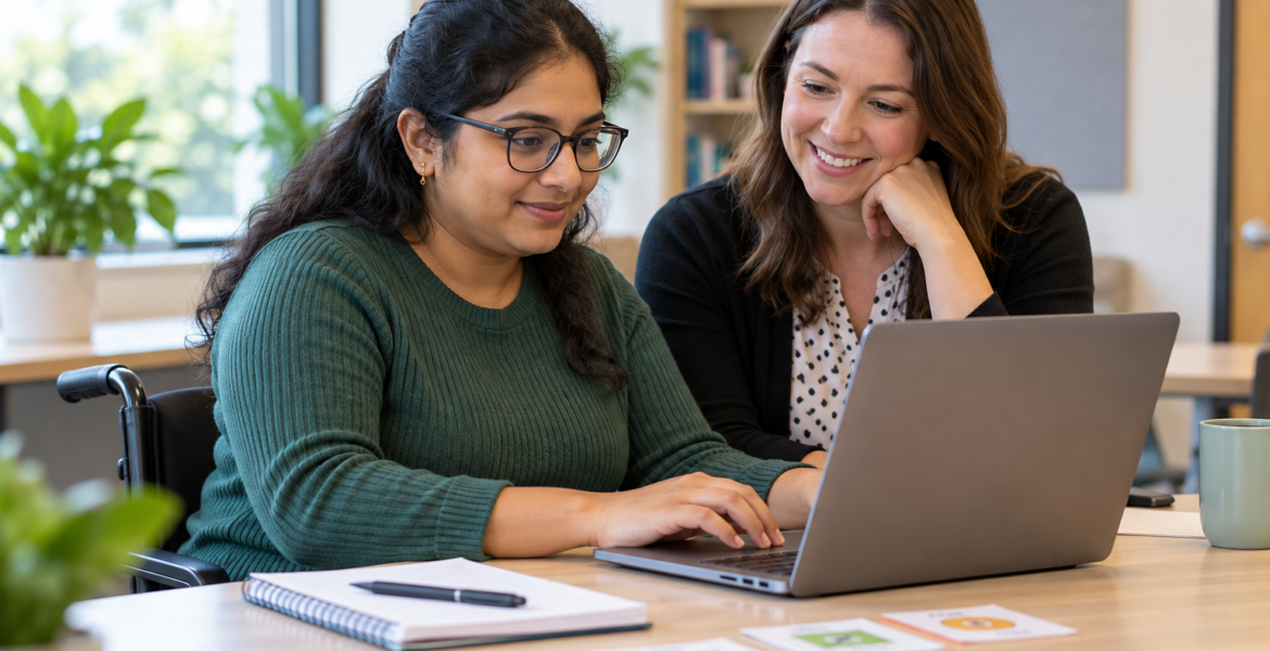 A learner using a laptop with a mentor in a technology training session.