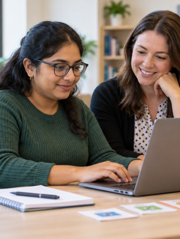 A learner using a laptop with a mentor in a technology training session.
