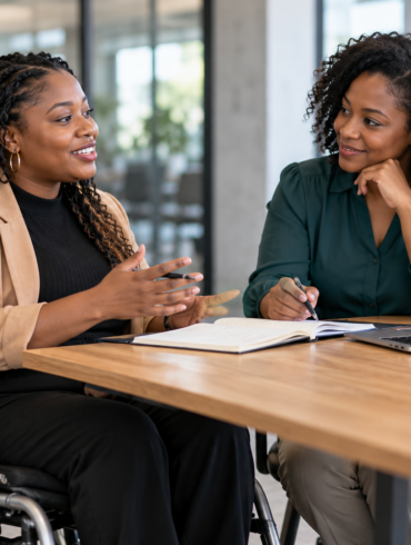A wheelchair user practicing an interview with a career coach at an office table.